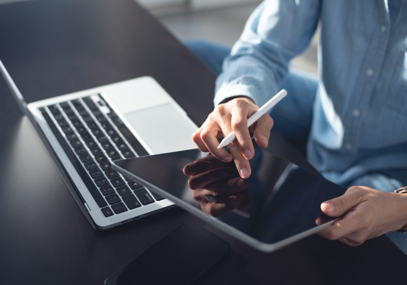 KT - 一位商务人士使用平板电脑和笔记本电脑的图片