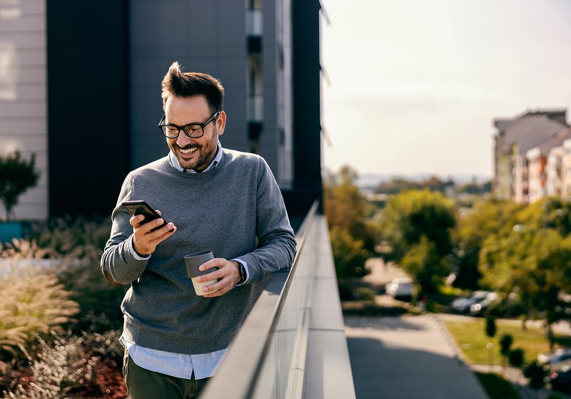KT - Man standing next to a bridge checking his phone